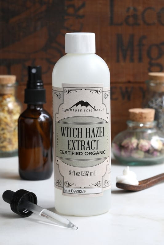 8 oz plastic bottle filled with Mountain Rose Herbs Organic Witch Hazel Extract surrounded by glass apothecary bottles