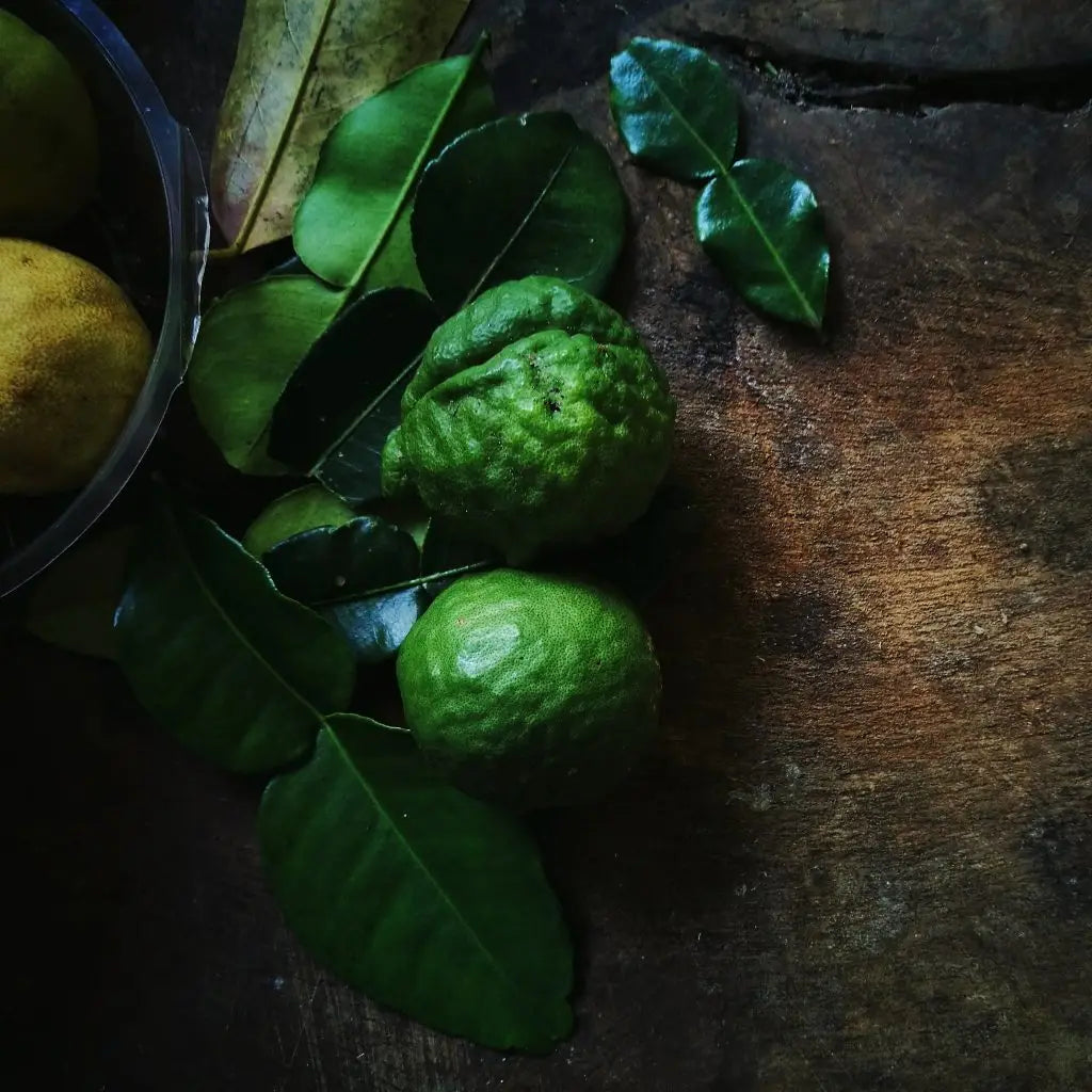 Fresh Kaffir limes with green leaves on wooden surface - Discover the Delight of Bergamot Tea.