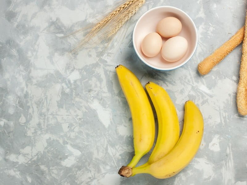 Top view yellow bananas with raw eggs and bun bread on light-white desk Free Photo - Cariblens