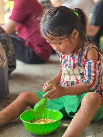 Young girl in Diên Khánh District, Vietnam pouring liquid into a bright green bowl.
