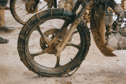 Muddy motorcycle wheel and suspension in Diên Khánh’s rural landscape, Vietnam.